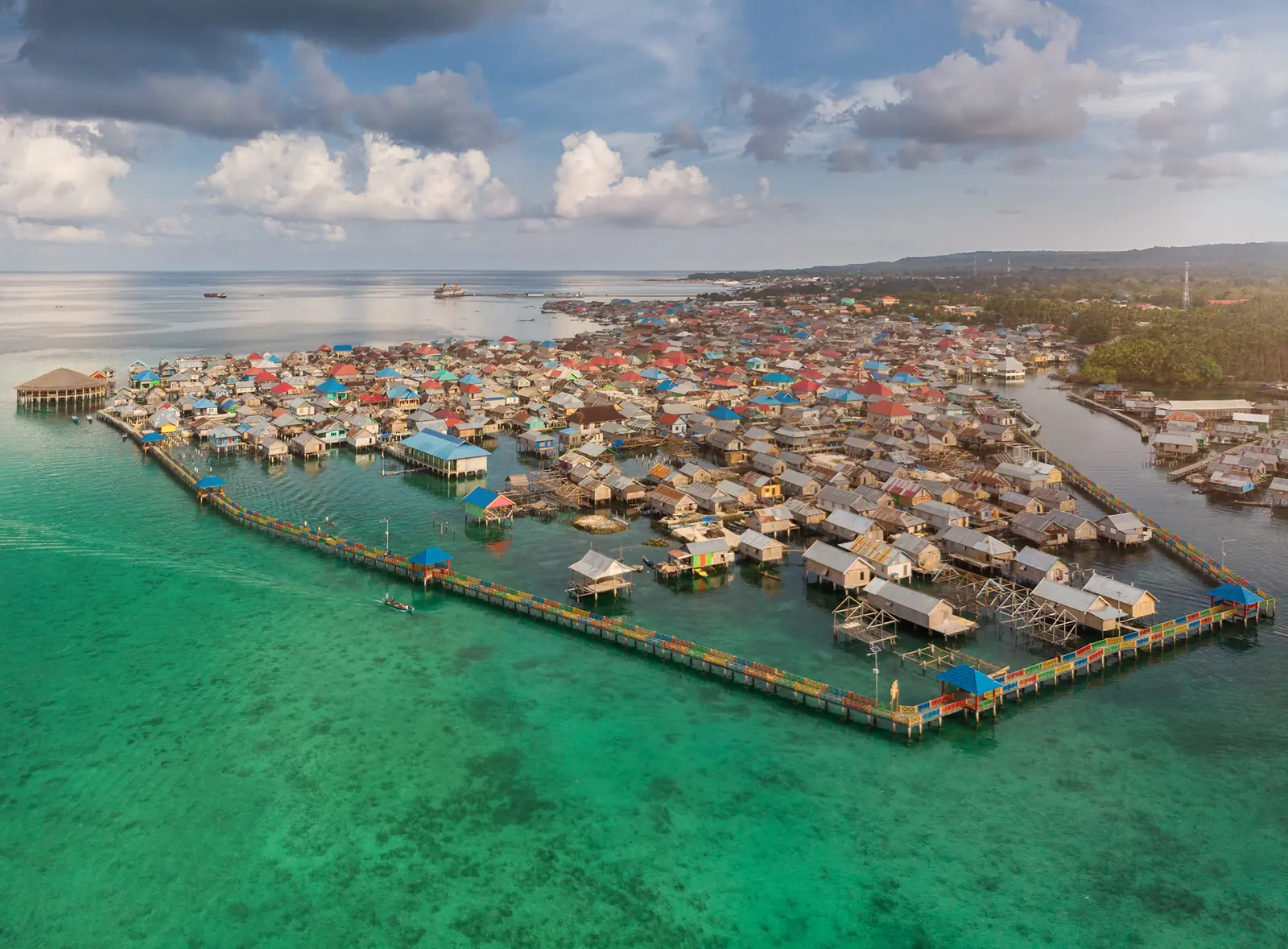 Panorama permukiman Bajo dengan rumah panggung dan titian di atas perairan hijau Pulau Wangi-Wangi